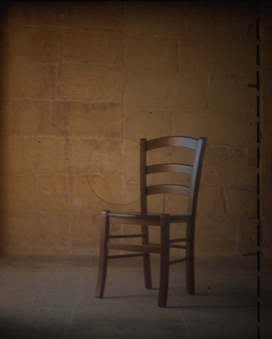 Wooden chair against a textured beige wall